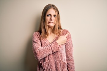 Young beautiful redhead woman wearing pink casual sweater over isolated white background Pointing...