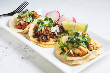 A view of a plate of street tacos, in a restaurant or kitchen setting.
