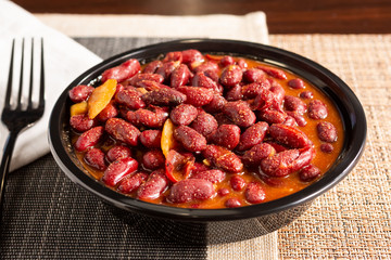 A closeup view of a bowl of Southern red beans, in a restaurant or kitchen setting.