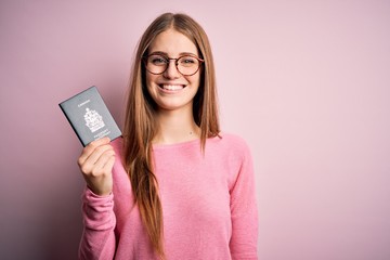 Beautiful redhead tourist woman holding canadian canada passport over pink bakcground with a happy face standing and smiling with a confident smile showing teeth