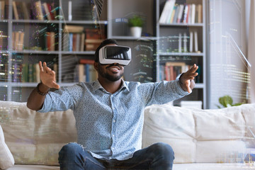 Excited African American young man in virtual reality glasses touch objects interact with 3D simulation, happy biracial male in VR goggles have fun testing new device, digital technology concept