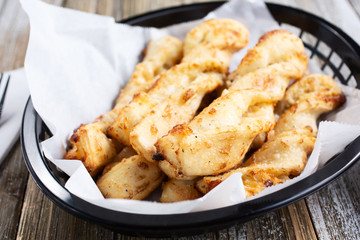 A closeup look of a basket full of breadstick twists, in a restaurant or kitchen setting.