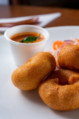 A view of a plate of Indian medu vada fritters, in a restaurant or kitchen setting.