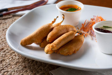 A view of a plate of mirchi bajji, an Indian stuffed green chili, in a restaurant or kitchen setting.