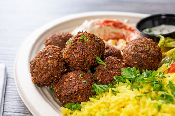 A closeup view of several falafel balls on an entree plate, in a restaurant or kitchen setting.