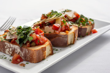 A closeup view of a plate of bruschetta, in a restaurant or kitchen setting.