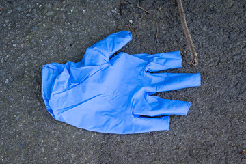 Used blue rubber glove being littered on the ground. People are littering their gloves. Coronavirus...