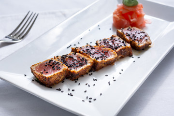 A view of a plate of seared ahi tuna, in a restaurant or kitchen setting.