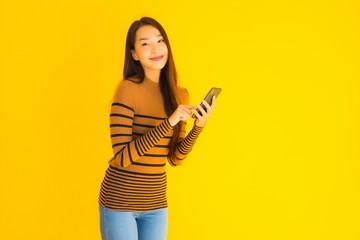 Beautiful young asian woman use smart mobile phone or cellphone with many action on yellow background