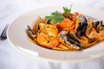 A view of a bowl of seafood fettuccine pasta, in a restaurant or kitchen setting.