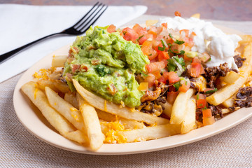 A view of a plate of carne asada fries, in a restaurant or kitchen setting.