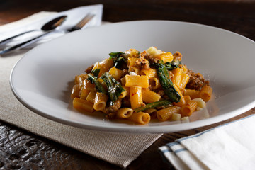 A view of a plate of rigatoni and sausage, restaurant or kitchen setting.