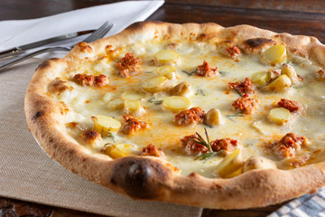 A view of an artisan pizza with potatoes and sausage, in a restaurant or kitchen setting.
