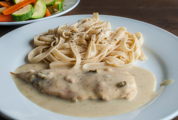 Macro photography or close up image of chicken breast with asparagus cream and pasta on a table