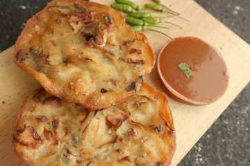 Bakwan goreng, Indonesian fried vegetables dough fritters, appetizer, traditional street food, served with sambal or chili sauce and raw chilli pepper