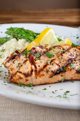 A closeup view of a salmon dinner plate, in a restaurant or kitchen setting.