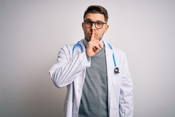 Young doctor man with blue eyes wearing medical coat and stethoscope over isolated background asking to be quiet with finger on lips. Silence and secret concept.