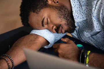 Fotobehang Close up of tired african American male worker or student feel fatigue exhaustion fall asleep at workplace, exhausted biracial man overwhelmed with work take nap sleep at office desk, overwork concept © fizkes