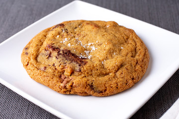 A closeup view of a chocolate chip cookies on a plate, in a restaurant or kitchen setting.