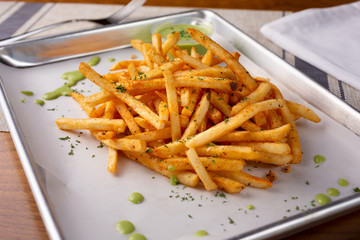 A closeup view of a tray of cajun style french fries in a restaurant or kitchen setting.