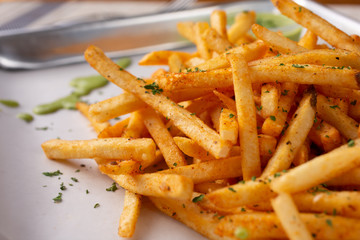 A closeup view of a tray of cajun style french fries in a restaurant or kitchen setting.