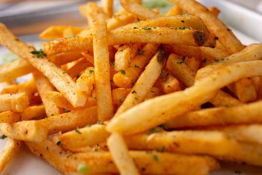 A closeup view of a tray of cajun style french fries in a restaurant or kitchen setting.