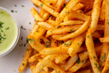 A closeup view of a tray of cajun style french fries in a restaurant or kitchen setting.