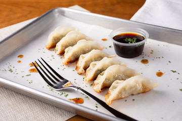 A view of an appetizer tray of Japanese gyoza, in a restaurant or kitchen setting.