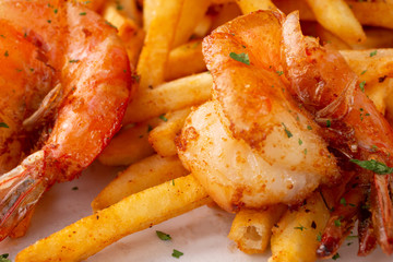 A closeup view of plate of fried shrimp and french fries, in a restaurant or kitchen setting.