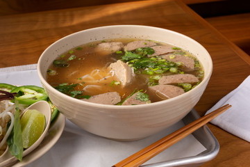 A view of a pho soup bowl with meatballs, in a restaurant or kitchen setting.