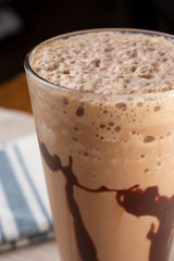 A closeup view of an iced mocha coffee drink in a glass, in a restaurant or kitchen setting.