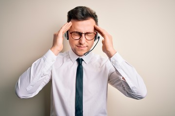 Young handsome caucasian business man wearing call center headset at customer service suffering from headache desperate and stressed because pain and migraine. Hands on head.