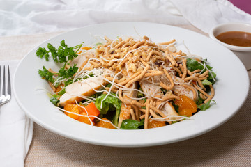 A view of a plate of Asian chicken salad, in a restaurant or kitchen setting.