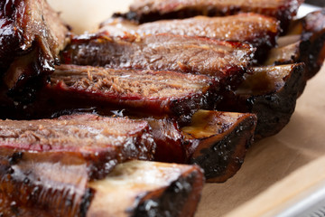 A closeup view of a rack of barbecue beef ribs on a tray, in a restaurant or kitchen setting.