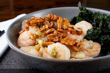 A closeup view of a bowl of honey walnut shrimp, in a restaurant or kitchen setting.