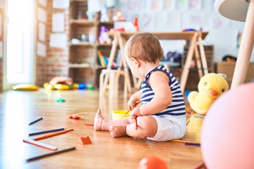 Adorable toddler playing around lots of toys at kindergarten