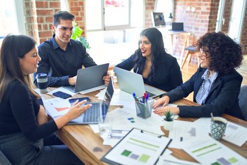 Group of business workers smiling happy and confident. Working together with smile on face  using laptop and speaking at the office
