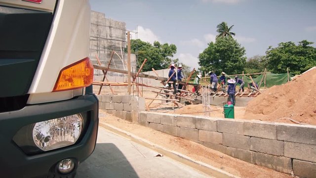 Builders work with concrete in Thailand. Asian people are building a building. Construction of a villa in Thailand. Builders working heavy equipment and workers pouring fresh cement from mixer truck