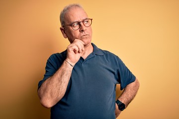 Middle age handsome hoary man wearing casual polo and glasses over yellow background with hand on...