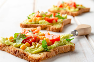 Vegan sandwich with avocado, nuts, vegetables and olive oil on white wooden