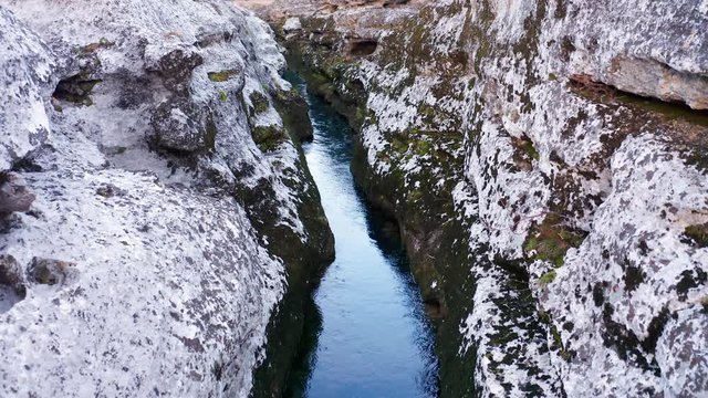 Narrow mountain river flowing through desolate rocky landscape. Stream bed cut deep into stones. Upstream of Cijevna (Cem) in Montenegro. Aerial footage.