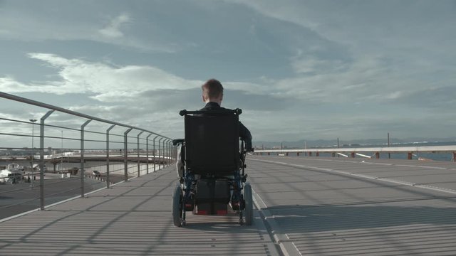 Following the disabled child having a lonely outdoor walk in electric wheelchair