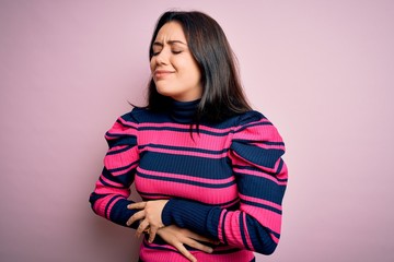 Fototapeta premium Young brunette elegant woman wearing striped shirt over pink isolated background with hand on stomach because indigestion, painful illness feeling unwell. Ache concept.