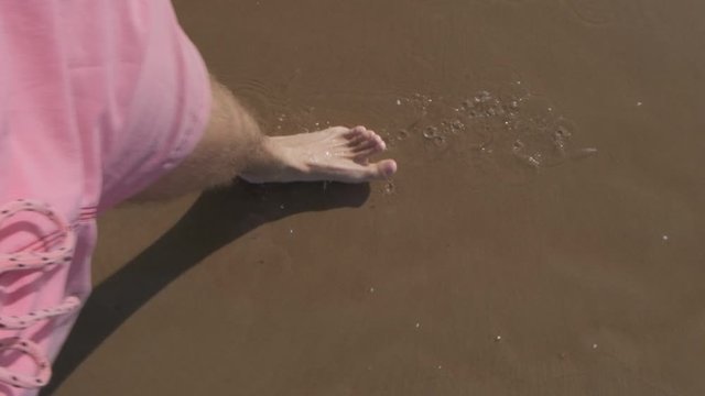 slow point of view motion video of the legs and foots of a young men walking on the sand and water of the beach of Solanas, Maldonado, Punta del Este