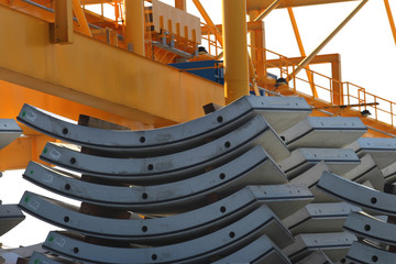 Curved interlocking pre cast concrete segments held in storage for the manufacture of and underground tunnel. Yellow outdoor overhead crane in the background
