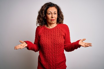 Middle age brunette woman wearing casual sweater standing over isolated white background clueless and confused with open arms, no idea concept.
