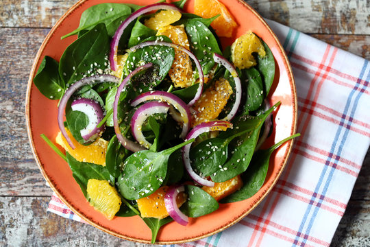 Healthy salad with spinach, tangerine and blue onions. Vegan food. Cooking at home. Beautiful food.
