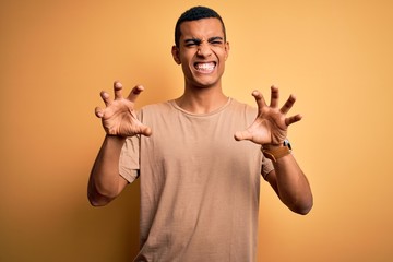Young handsome african american man wearing casual t-shirt standing over yellow background smiling...