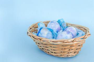 Fototapeta na wymiar Easter basket with colorful cosmic eggs close-up on a blue background. Happy Easter card