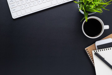 Workplace in office with black desk. Top view from above of keyboard with notebook and phone. Space for modern creative work of designer. Flat lay with blank copy space. Business and finance concept.